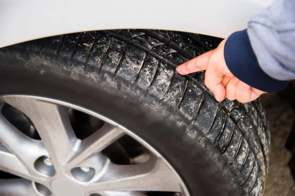 Main pointant la bande de roulement illustrant le contrôle d’un pneu 4 saisons adapté à toutes les conditions