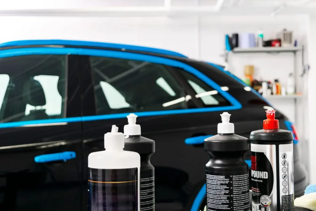 Voiture noire masquée autour des vitres avec produits de polish en premier plan dans un atelier de detailing