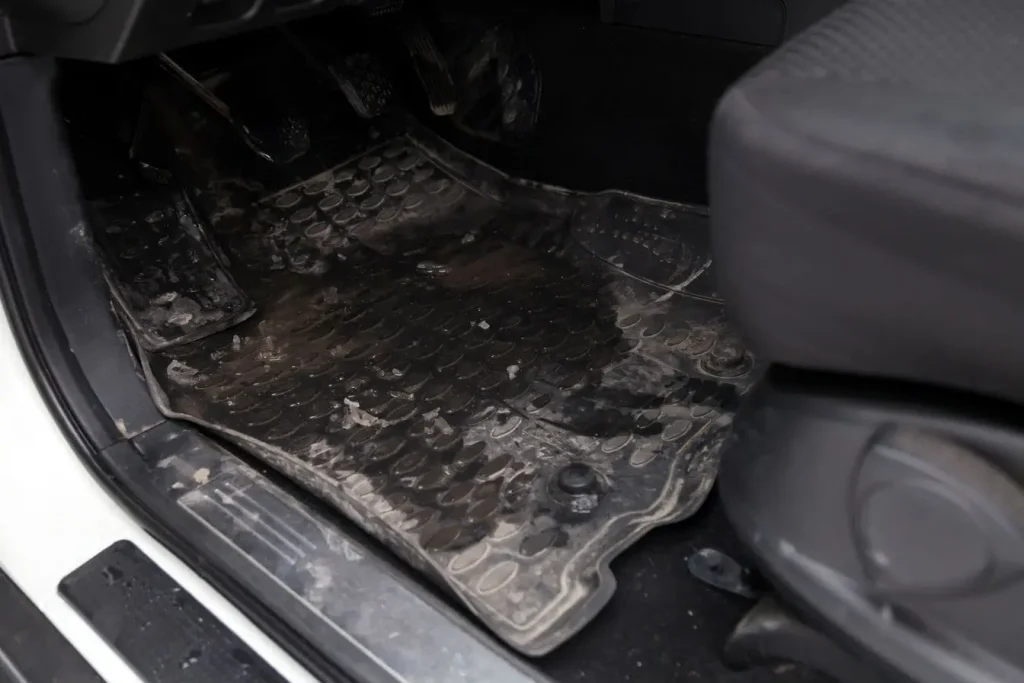 Tapis en caoutchouc conducteur avec traces de boue illustrant une protection intérieure de voiture