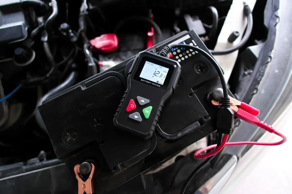 Batterie de voiture avec testeur branché illustrant une vérification avant utilisation d’un booster de batterie