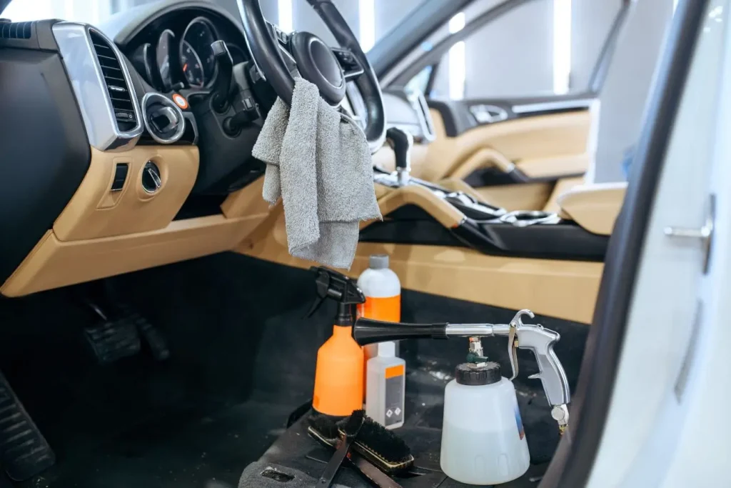 Intérieur de voiture beige et noir avec produits de nettoyage au sol, illustration des étapes de réparation plastique intérieur automobile