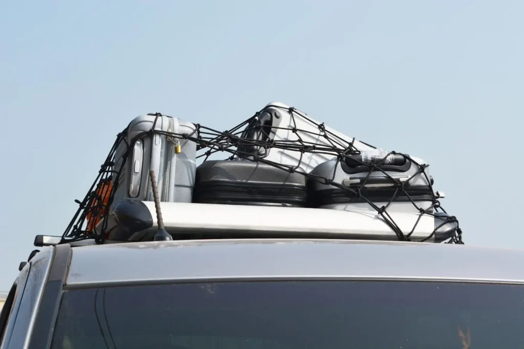 Toit de voiture chargé de valises argentées et noires, image d’une charge maximale maîtrisée