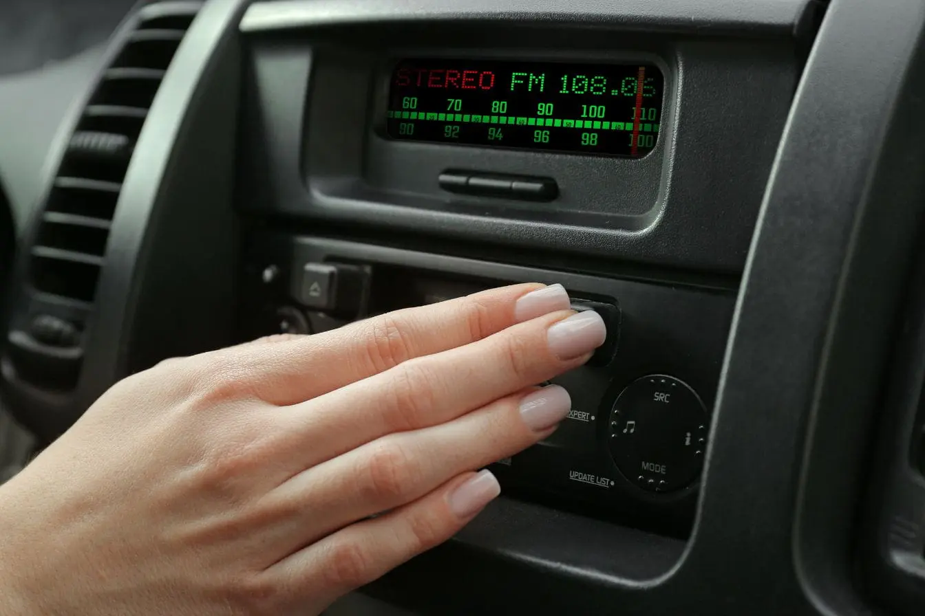autoradio Main ajustant bouton d’un autoradio affichant fréquence FM