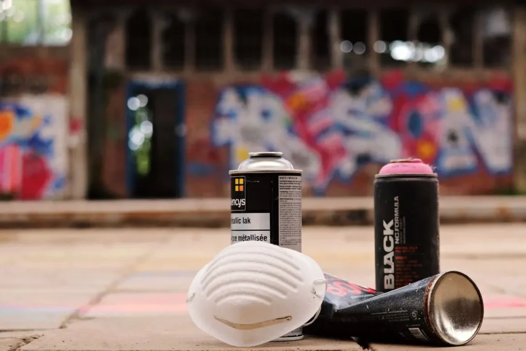 Trois bombes de peinture posées au sol illustrant l’usage du vernis carrosserie pour protéger et sublimer la brillance des surfaces automobiles