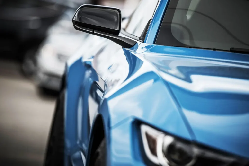 Surface brillante d’une voiture bleue avec détails nets, reflétant l’usage de cire de carrosserie pour protection et esthétique