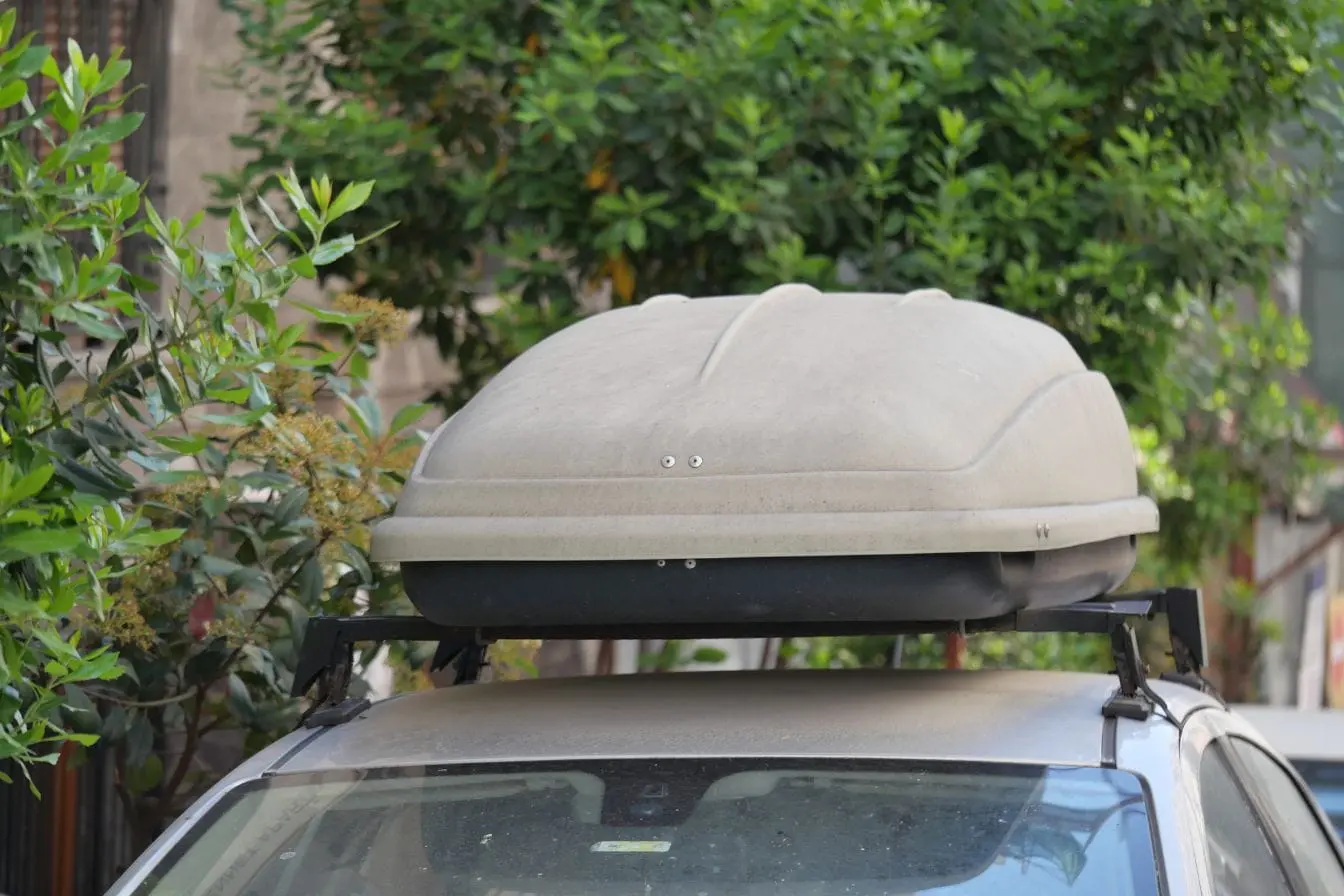 coffre de toit Voiture stationnée avec coffre de toit rigide, image illustrant un accessoire pratique pour transporter des bagages supplémentaires en voyage