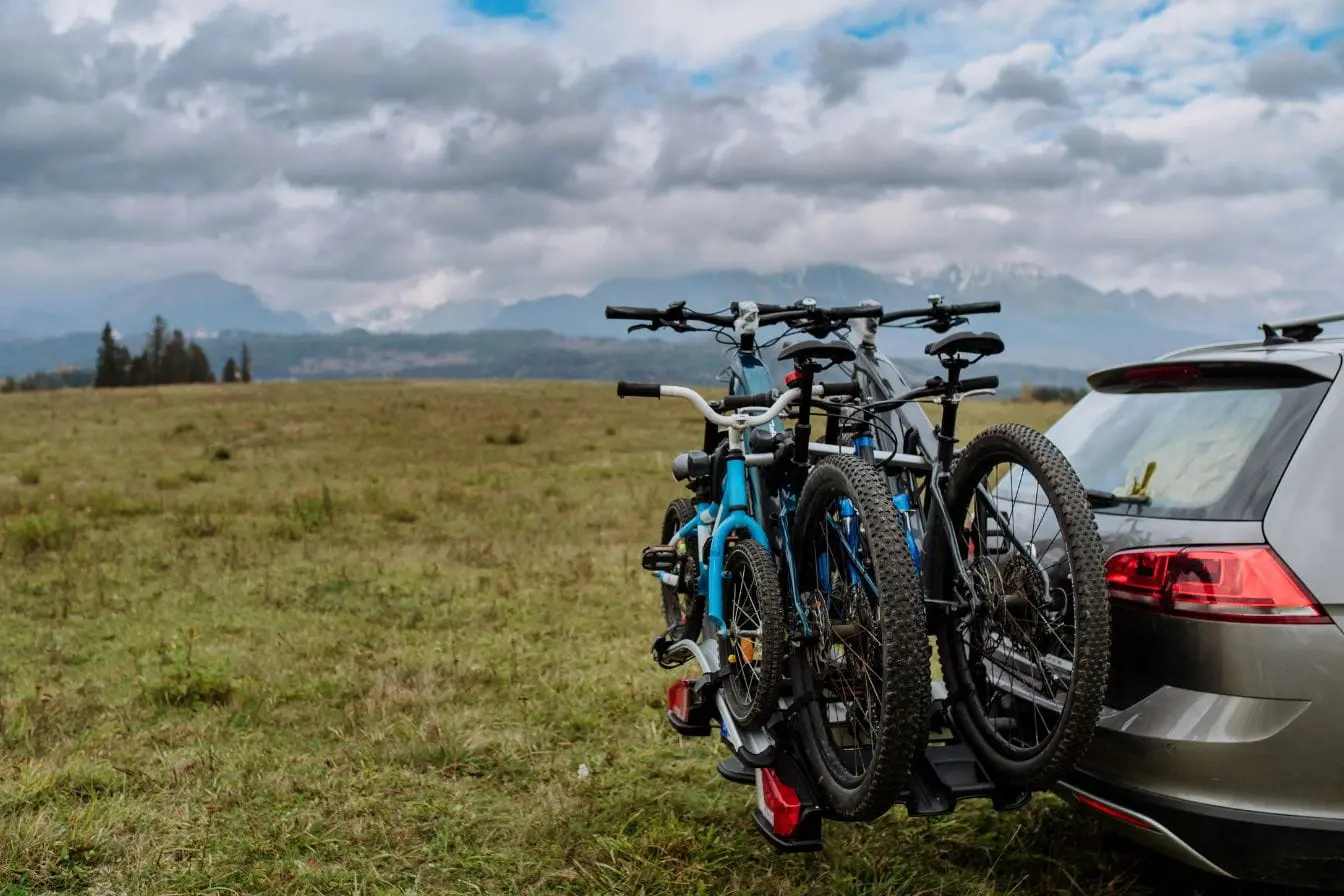 porte-vélo arrière SUV argenté garé sur champ avec porte-vélo arrière transportant quatre VTT, illustrant la praticité du porte-vélo pour aventures en plein air