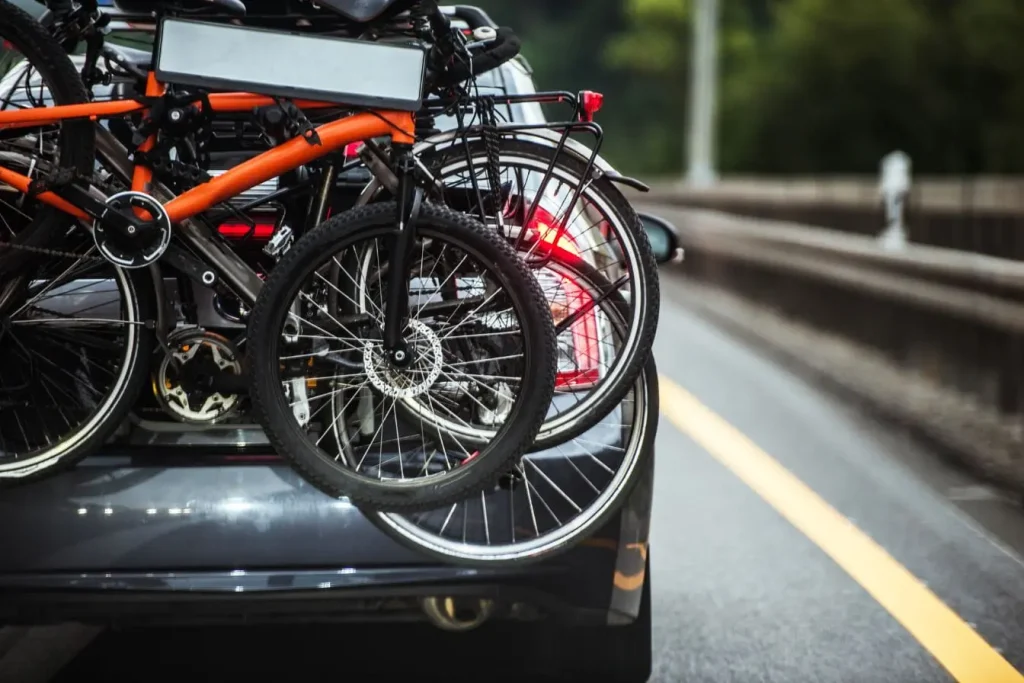 Voiture roulant sur route avec deux vélos fixés à un porte-vélo arrière, illustrant la praticité du porte-vélo pour voyages et activités sportives