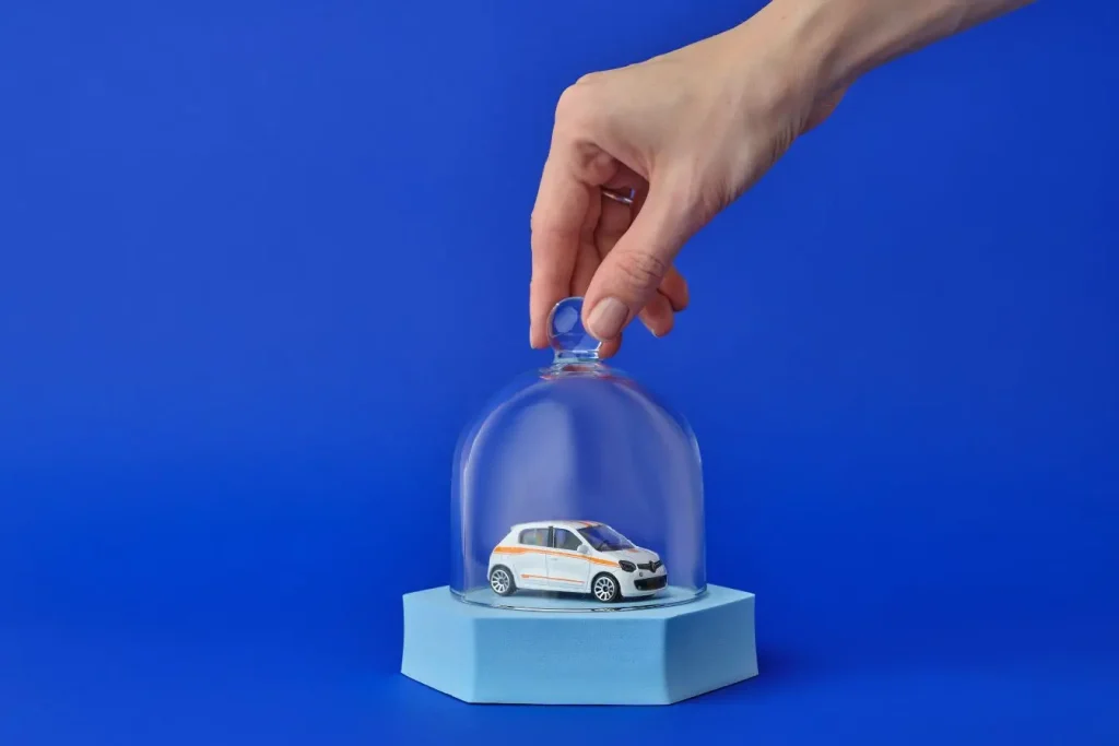 Voiture miniature blanche sous cloche de verre, image illustrant la différence entre assurance auto au tiers limitée et assurance tous risques protectrice.