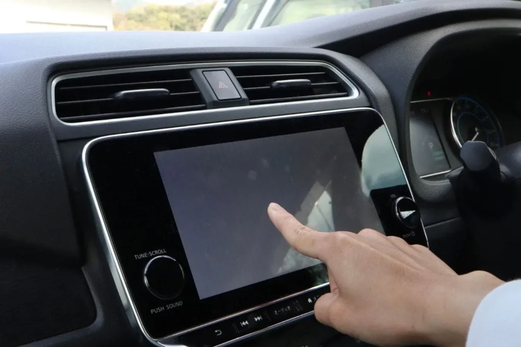 Main d'un technicien installateur en train de presser l'écran d'un nouvel autoradio tactile double DIN pour finaliser la configuration après le montage