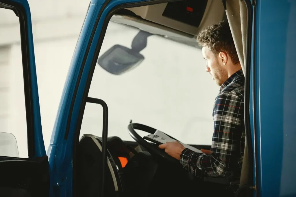 Conducteur assis dans cabine de camion bleu avec dossier en main, image illustrant la rédaction d’un constat amiable après un incident routier.