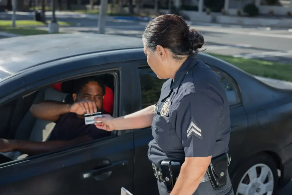 Scène de contrôle routier avec policier recevant carte d’un automobiliste, symbole de sensibilisation et récupération de points de permis.
