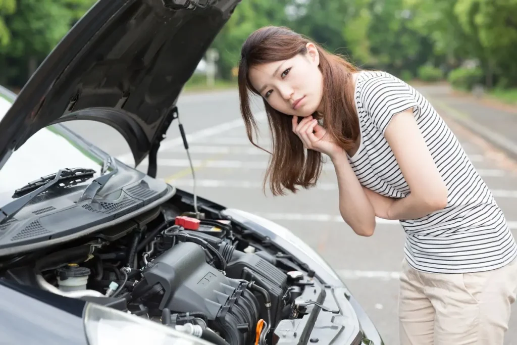 Personne inspecte le compartiment moteur d’une voiture, image illustrant la protection du carter moteur et l’importance de l’entretien automobile