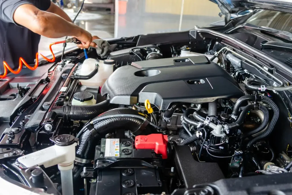Gros plan sur un moteur de voiture en cours d’entretien avec outil pneumatique, image illustrant la protection du carter moteur et la sécurité mécanique