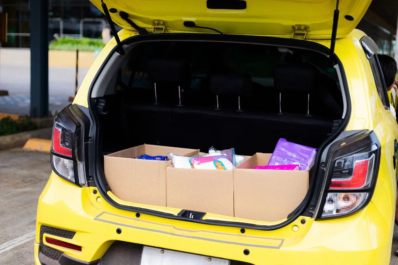 organisateur de coffre voiture Coffre jaune ouvert avec cartons et sacs colorés, image d’un organisateur de coffre voiture qui optimise le rangement et la praticité au quotidien