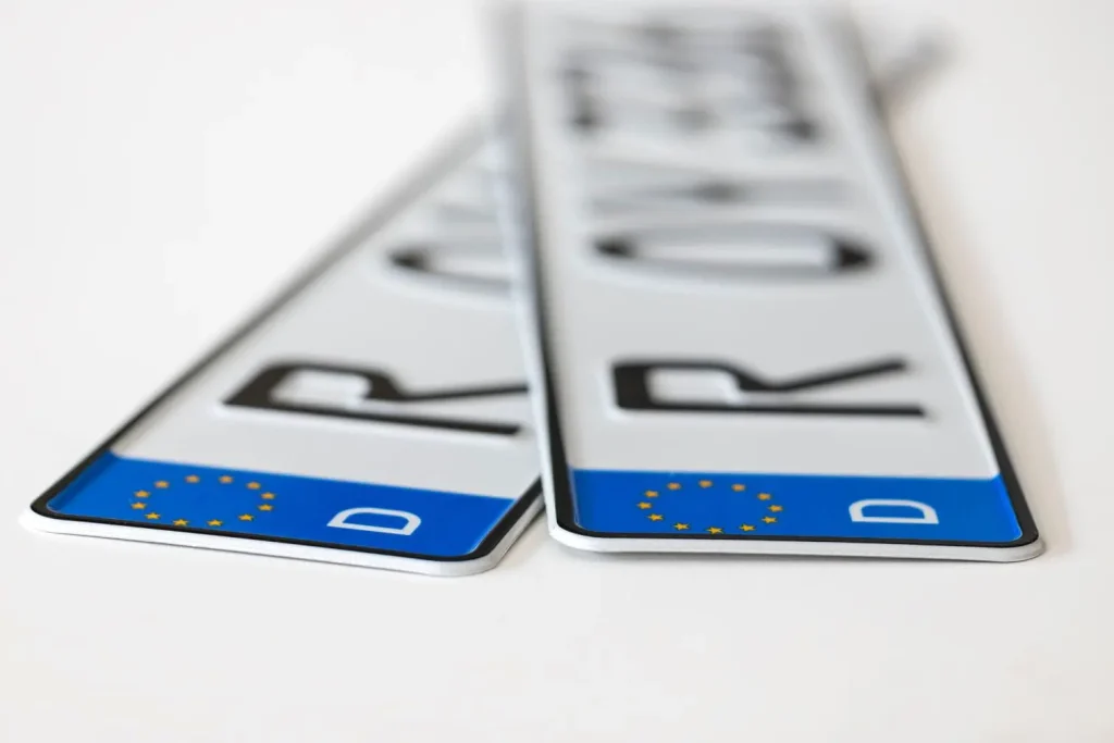 Deux plaques d’immatriculation européennes posées côte à côte sur fond blanc illustrant l’usage d’un cache-plaque amovible pour masquer temporairement les numéros.