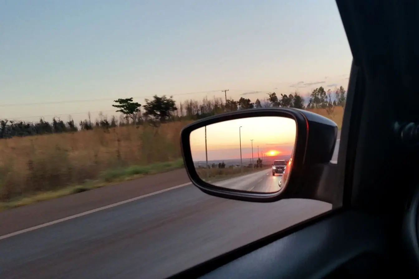 Vue depuis une voiture avec rétroviseur reflétant un coucher de soleil