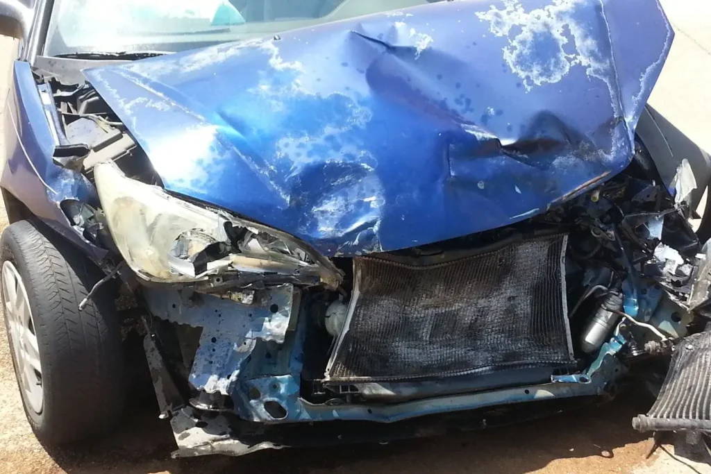 Véhicule endommagé avec capot écrasé et phares brisés, image représentant la nécessité d’un constat amiable après accident.