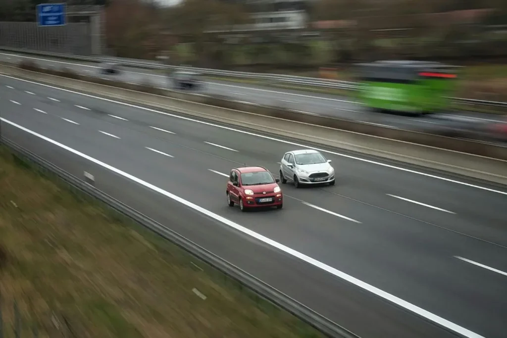 Deux voitures circulant côte à côte sur autoroute, image évoquant l’importance de respecter la distance de sécurité pour éviter les collisions.