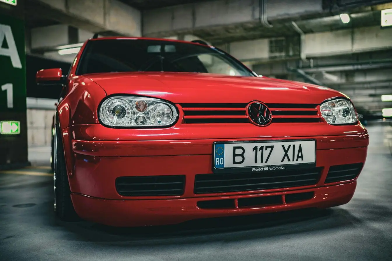 Voiture rouge Voiture rouge stationnée en parking, image illustrant le calcul du cheval fiscal et du coût réel d’une carte grise pour immatriculation.