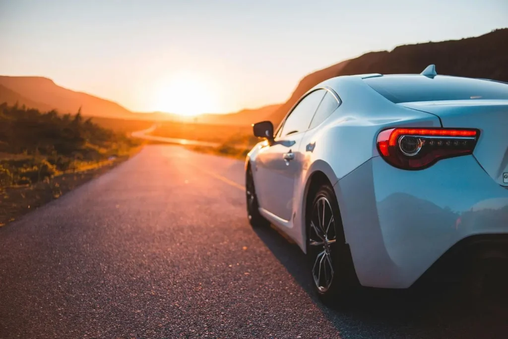 Voiture sportive neuve garée sur route au coucher du soleil, illustrant la décote qui réduit sa valeur dès qu’elle quitte le concessionnaire.