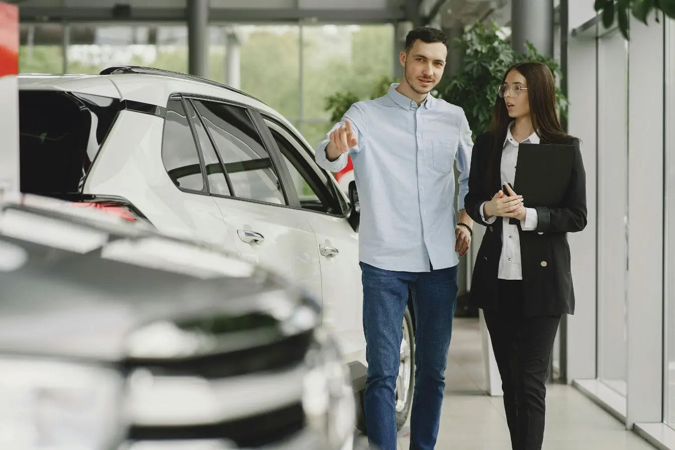 Discussion entre acheteur potentiel et vendeur devant SUV blanc, symbole d’un achat de voiture d’occasion