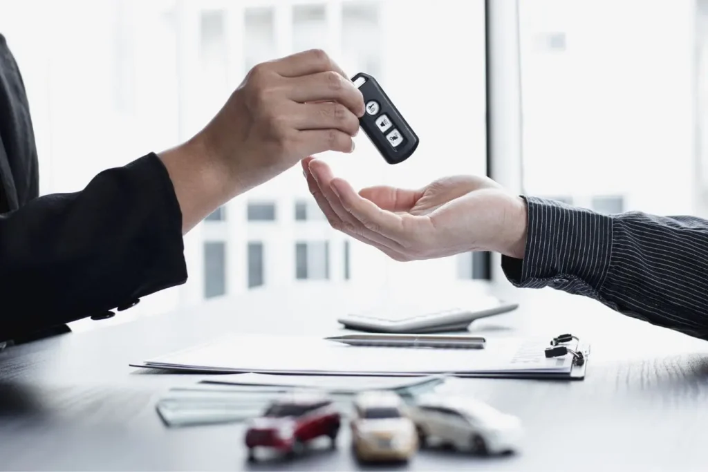 Gros plan sur mains échangeant clé de voiture au-dessus de documents, image illustrant l’évaluation argus voiture lors d’une transaction automobile.