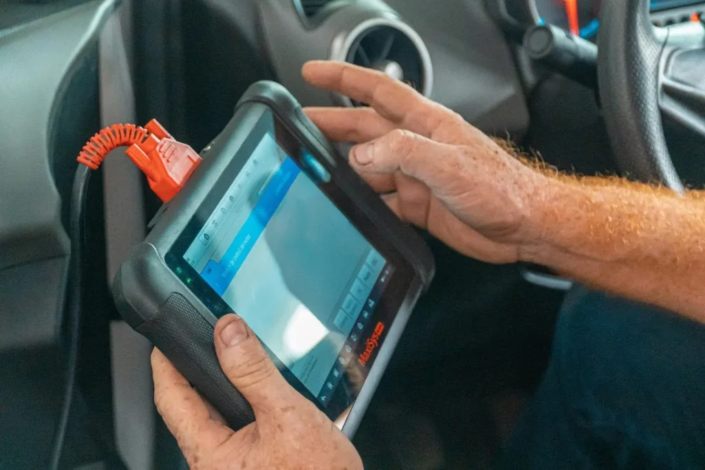 Gros plan sur outil de diagnostic connecté à une voiture, symbole des solutions pour identifier un compteur kilométrique trafiqué.