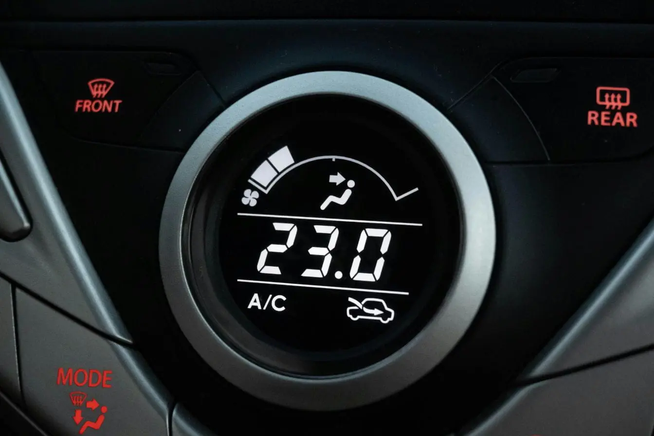 climatisation Affichage numérique indiquant 23°C avec icônes de ventilation, illustrant l’importance de l’entretien de la climatisation de voiture pour confort et sécurité.