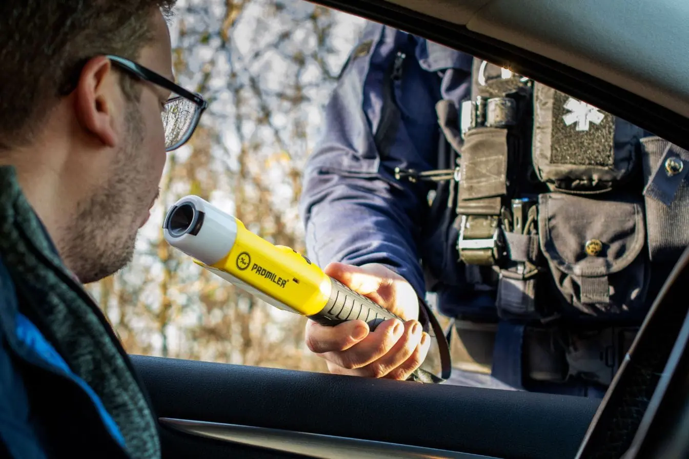 Conducteur soufflant dans un éthylotest tenu par un policier, image qui illustre le contrôle du taux d’alcoolémie légal en Europe.