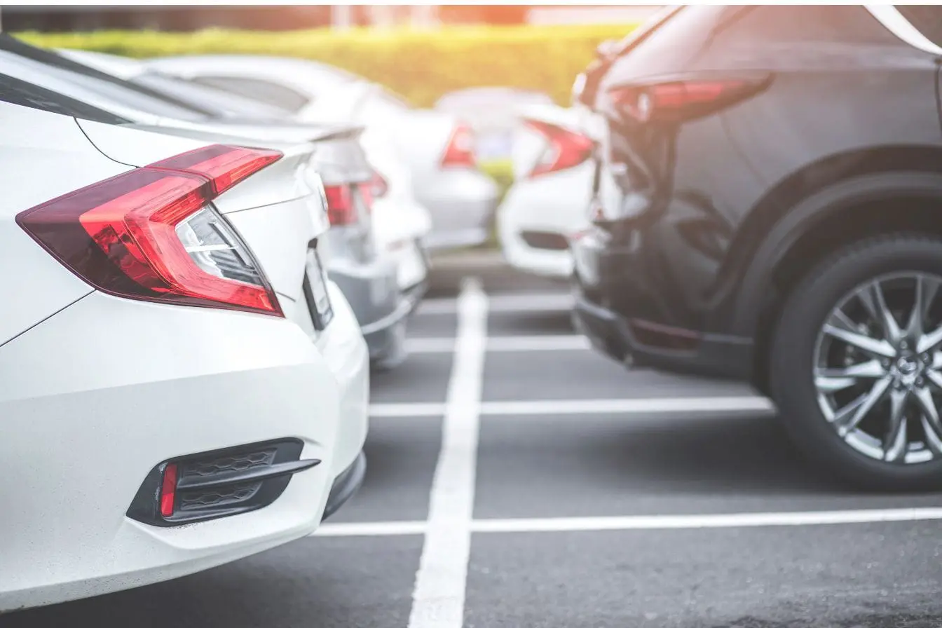 Voitures alignées sur parking Voitures alignées sur parking en pente douce, image qui illustre la question de stationner en côte sans utiliser le frein à main.