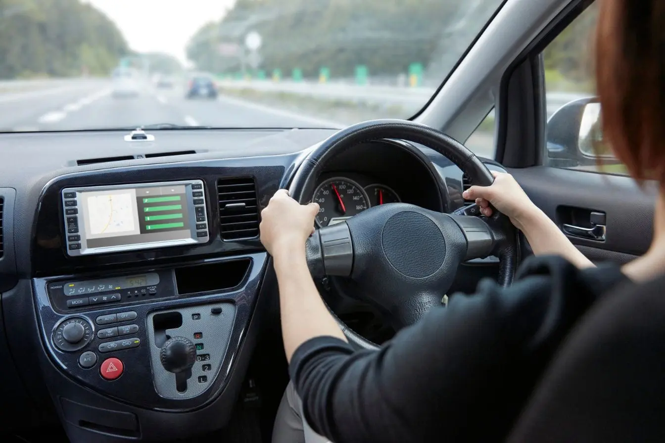 HUD Conducteur tenant le volant avec écran central affichant carte et données, image qui illustre l’utilité du HUD pour guider et informer en temps réel.