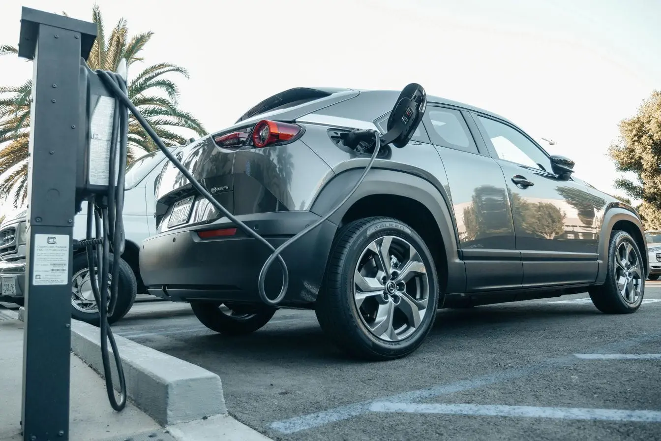 Voiture électrique Voiture électrique grise branchée à une borne, image qui illustre la recharge et rappelle le rôle du freinage régénératif dans la récupération d’énergie.
