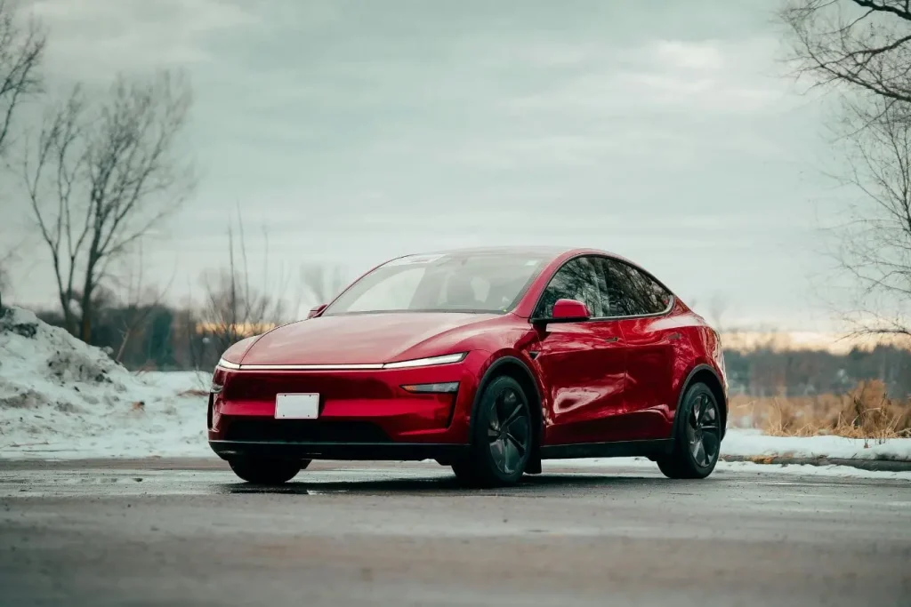 Voiture électrique rouge garée sur route humide, image qui illustre le rôle du freinage régénératif pour transformer l’énergie de décélération en recharge de batterie.