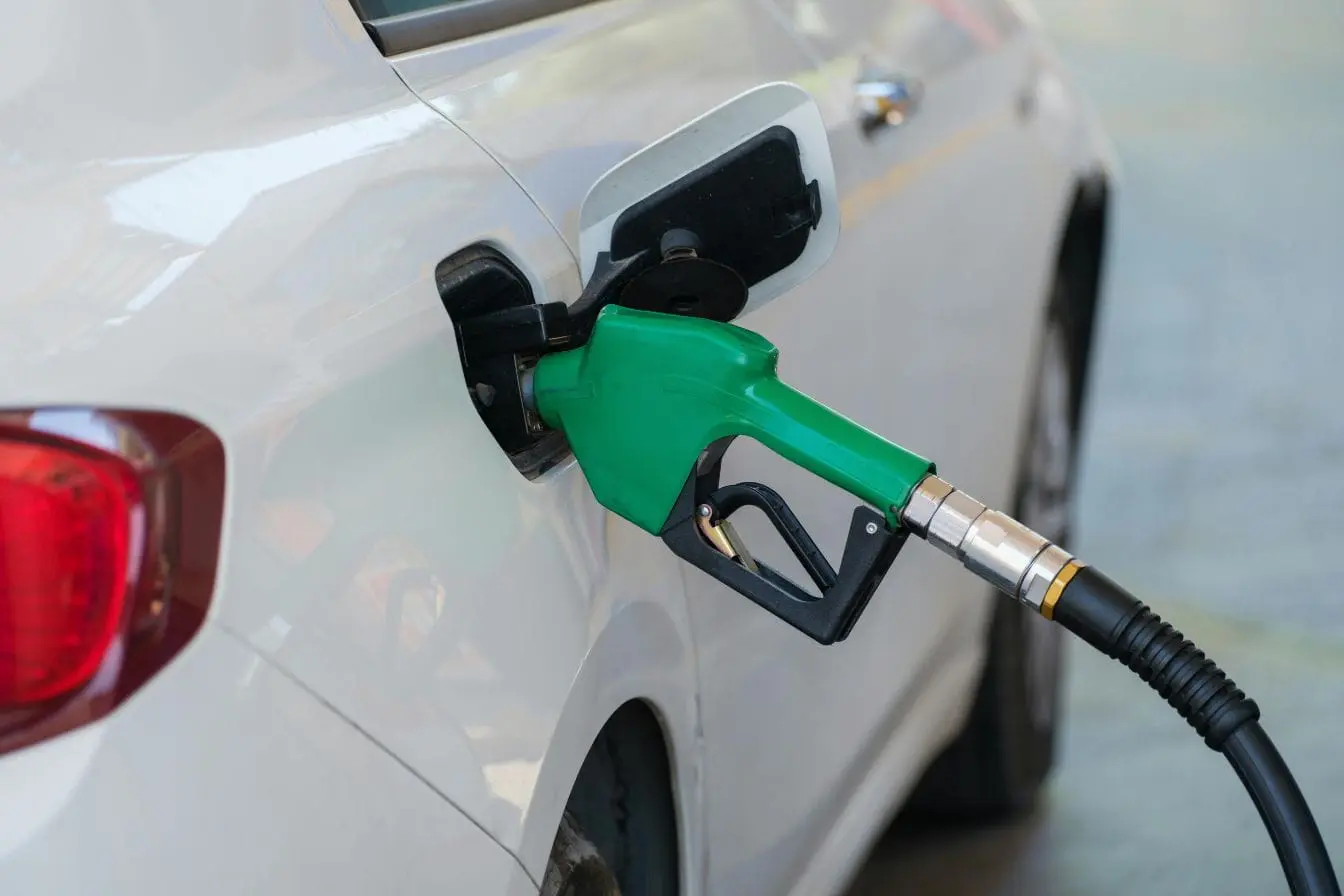 Pistolet vert inséré dans réservoir ouvert, symbole du carburant HVO diesel vert et de son impact environnemental.
