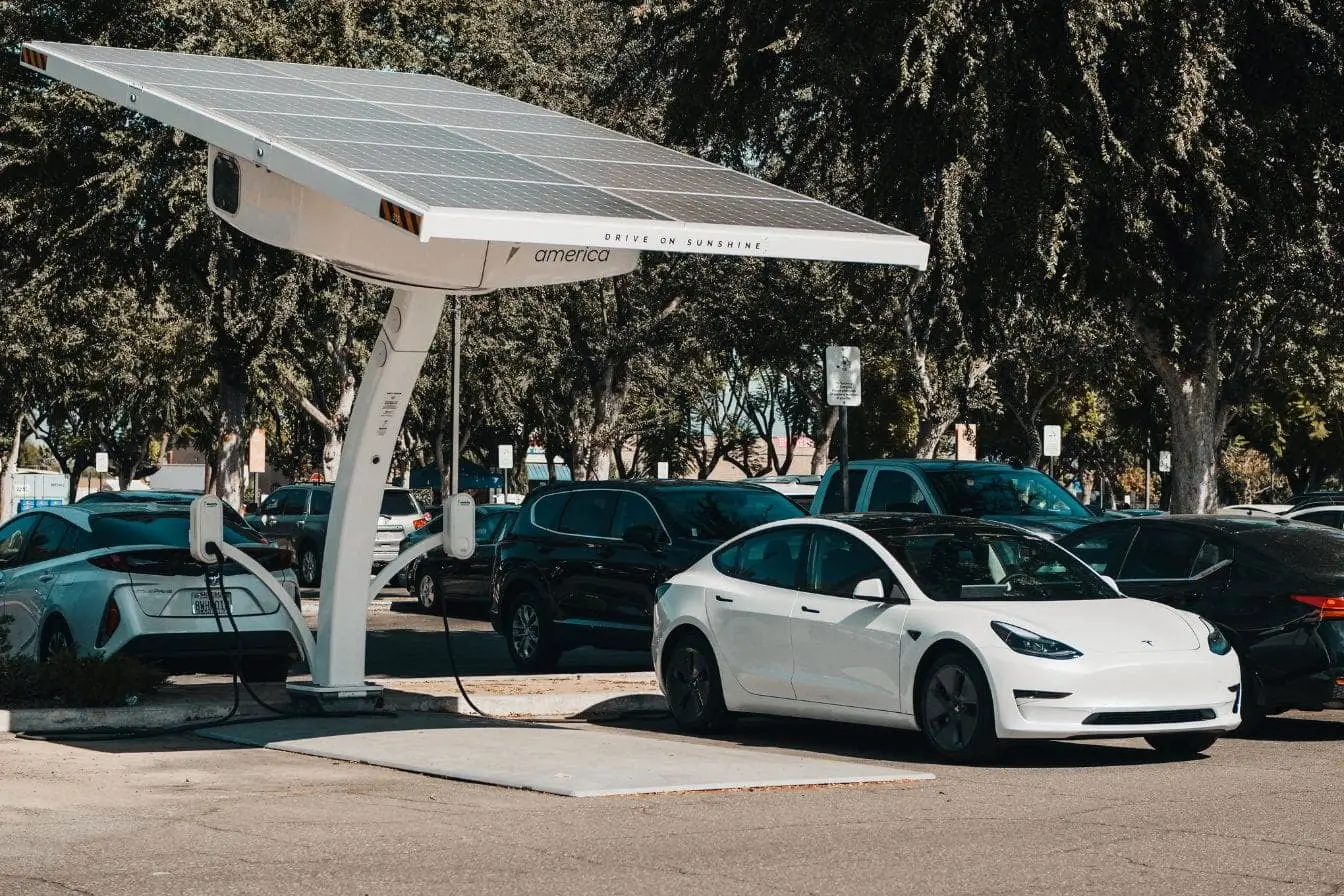 recharge d’une voiture électrique via énergie solaire Parking avec borne solaire et voiture branchée, image qui traduit la recharge d’une voiture électrique via énergie solaire.