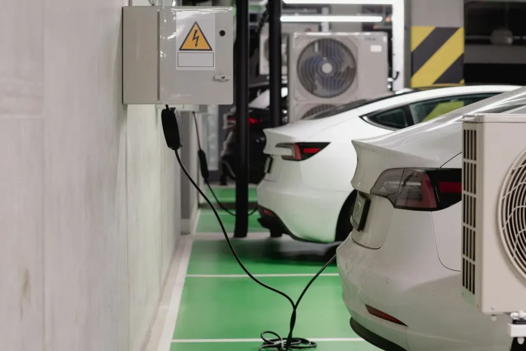 Parking intérieur avec voitures électriques, illustration des différents types de connecteurs.