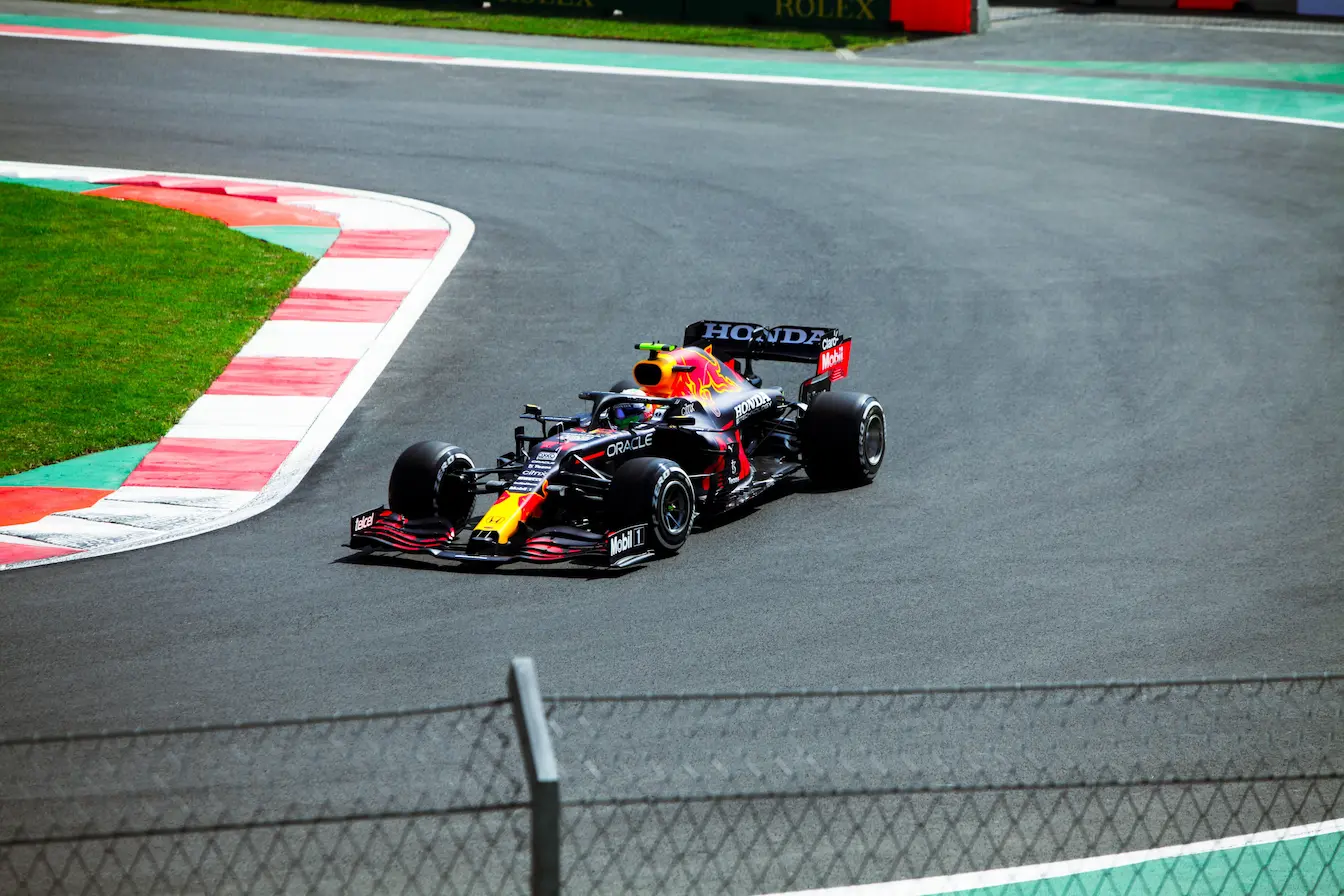Voiture de course aux couleurs rouge, blanche et bleue filant sur circuit, reflet de la vitesse et de la précision en Formule E.
