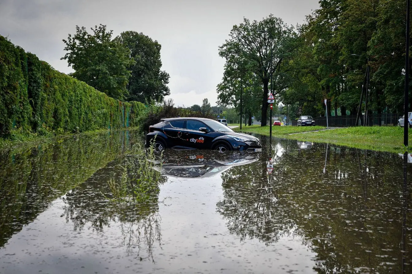 Voiture noire partiellement submergée dans eau de crue, reflet des réflexes à adopter après une catastrophe naturelle.