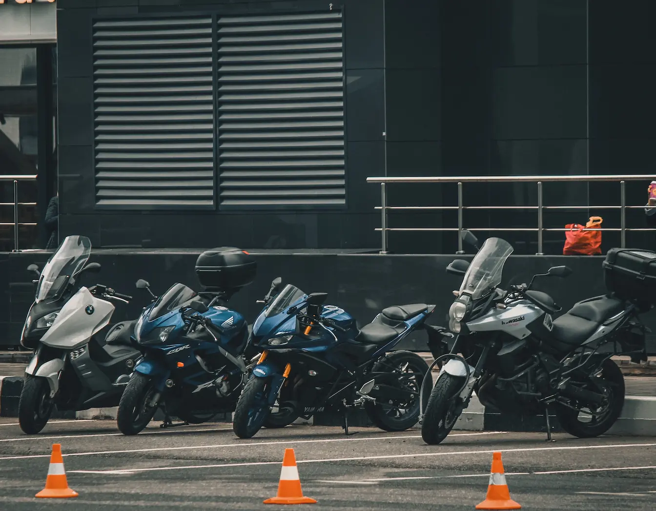 motos alignées Cinq motos alignées sur sol pavé avec cônes orange, image qui illustre la différence entre permis A1 et A2.