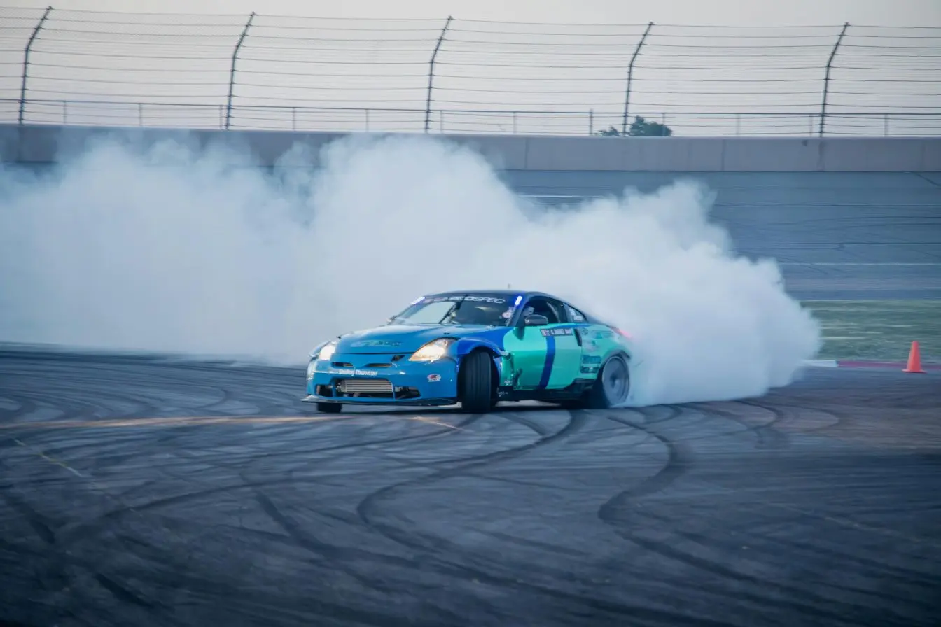 Voiture de sport bleue et verte en plein drift sur circuit, symbole des performances extrêmes liées aux records de vitesse automobile.