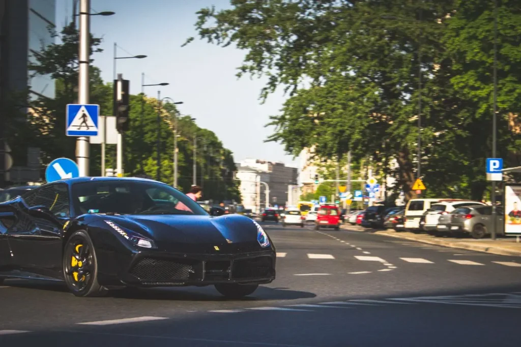 Ferrari noire roulant en ville, symbole des grandes marques automobiles de prestige comme Bugatti.