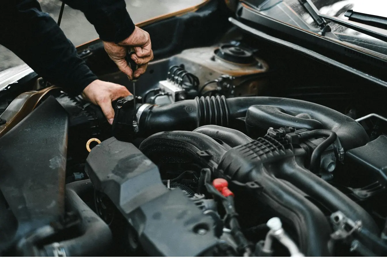 moteur Un mécanicien travaillant sur le compartiment moteur d'une voiture, idéal pour illustrer l'entretien et l'histoire du moteur diesel.