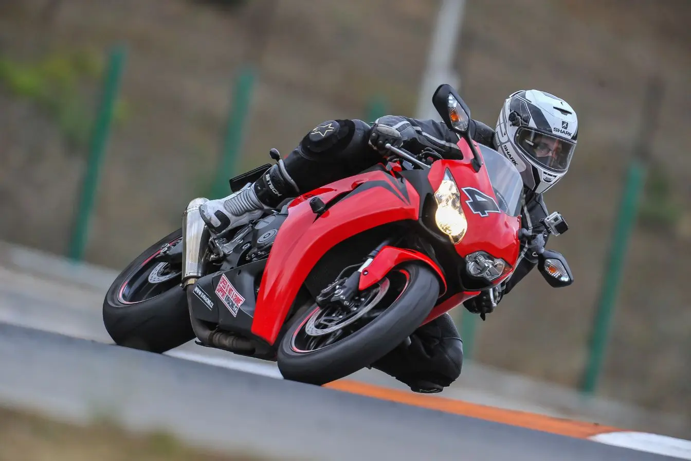 Moto rouge sportive penchée dans virage de circuit, symbole de vitesse extrême et des records en 2026.