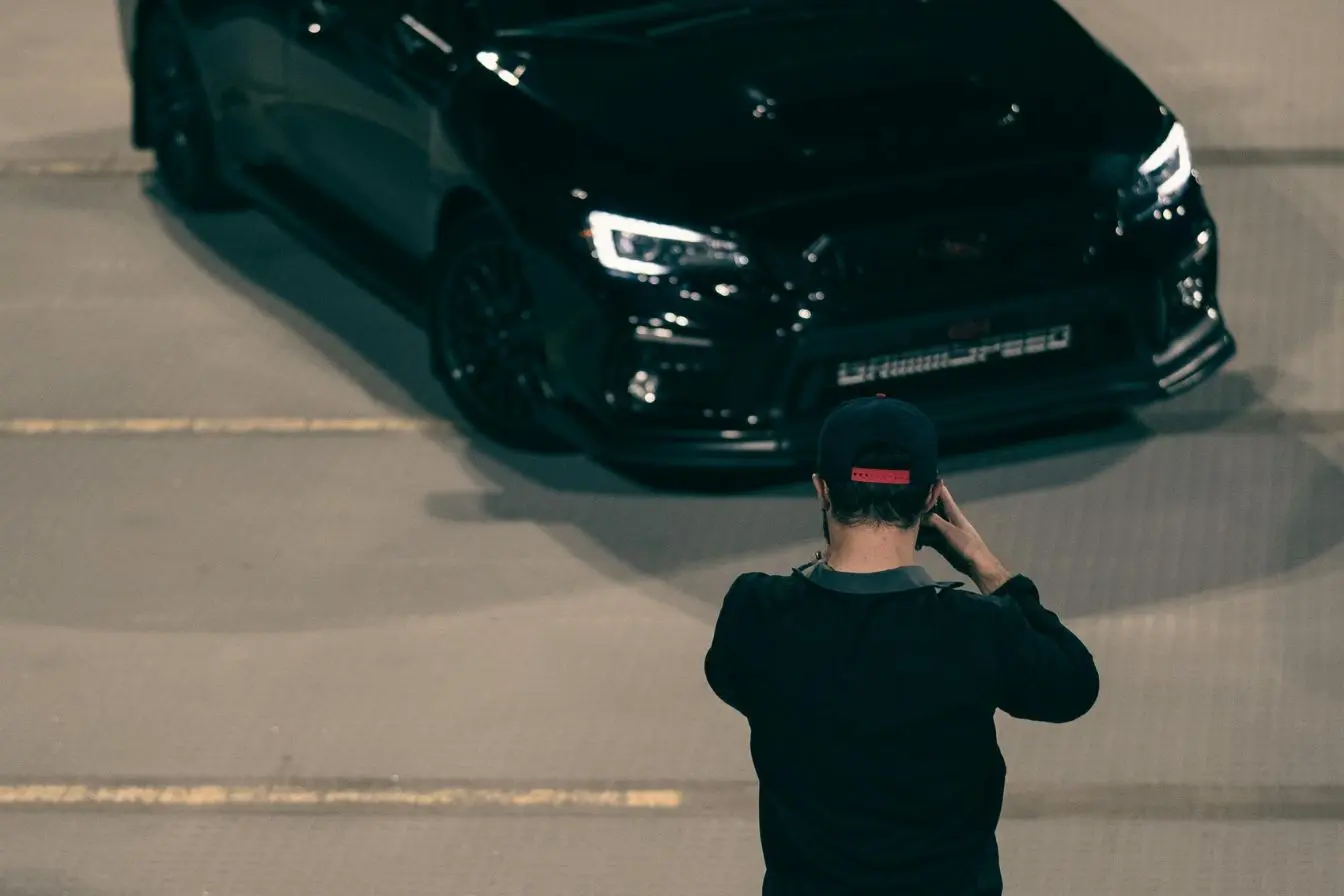 photographe automobile Personne réalisant une séance photo devant une voiture de sport aux lignes élégantes, représentant les premiers pas pour devenir photographe automobile
